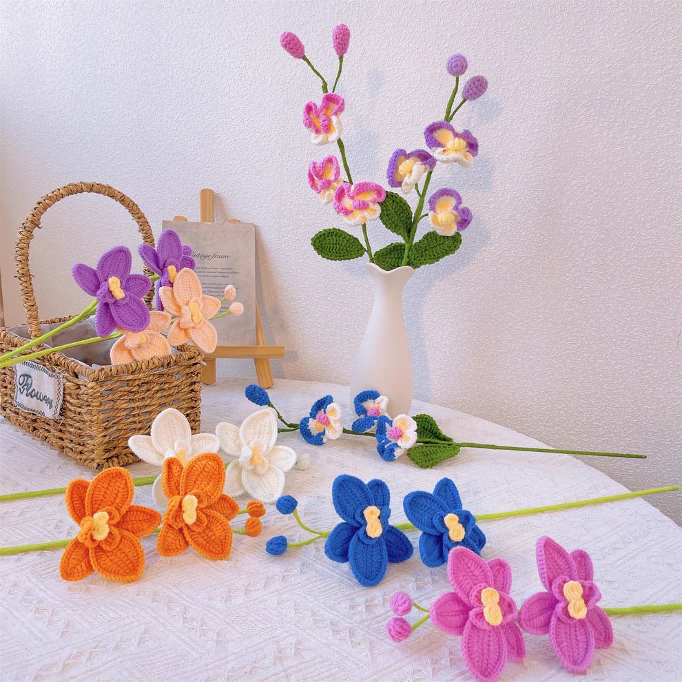 Crocheted orchids in vibrant colors arranged on white cloth with woven basket