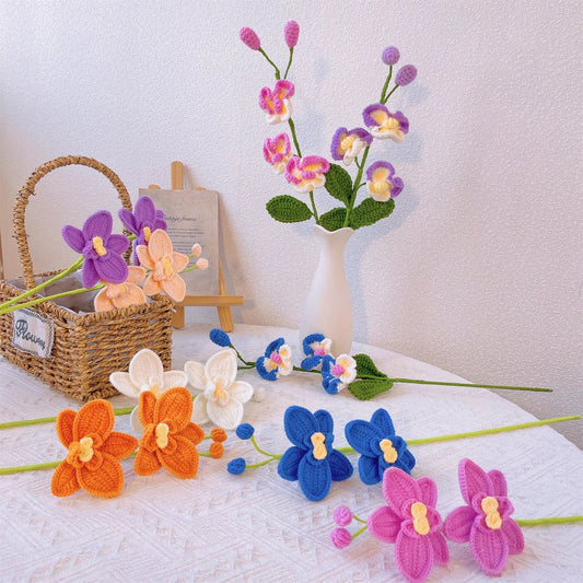 Crocheted orchids in vibrant colors arranged on white cloth with woven basket