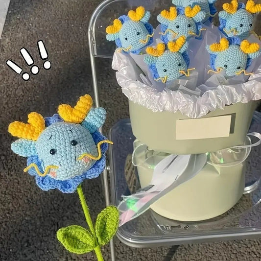 Crocheted blue and yellow dragon flowers in a white gift container with ruffled lining