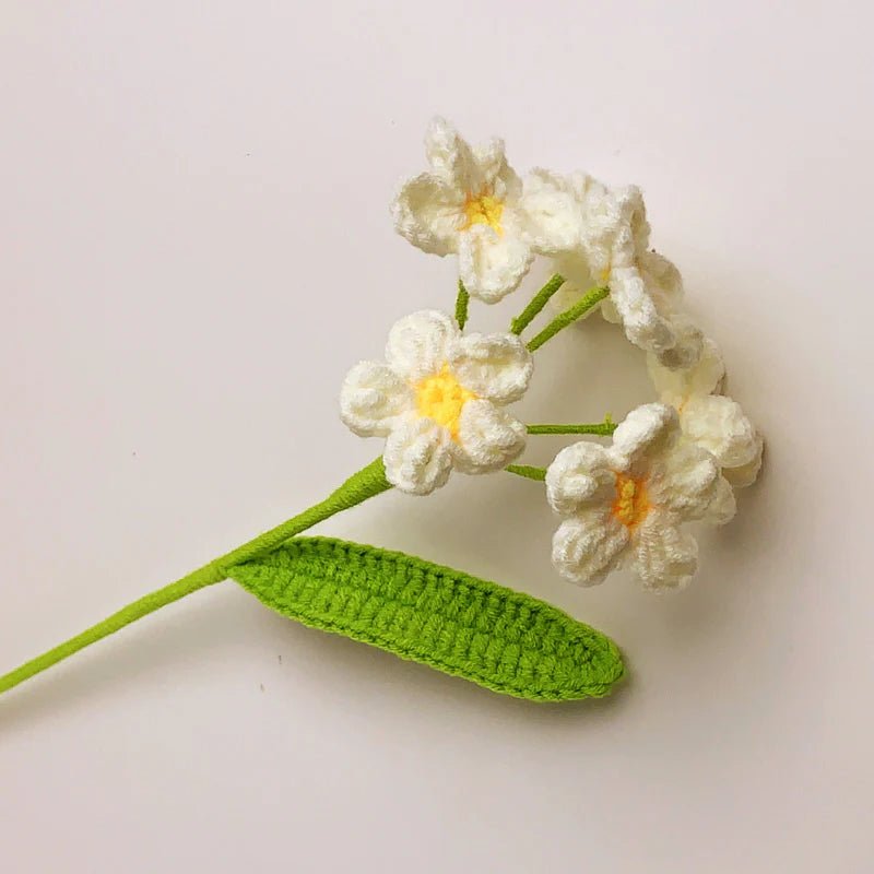 Crocheted white jasmine flowers with yellow centers and green leaf, handmade craft