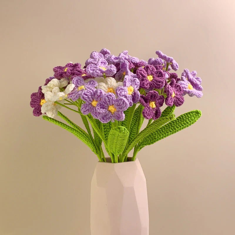 Crocheted bouquet of purple and white flowers with green leaves in a pale vase