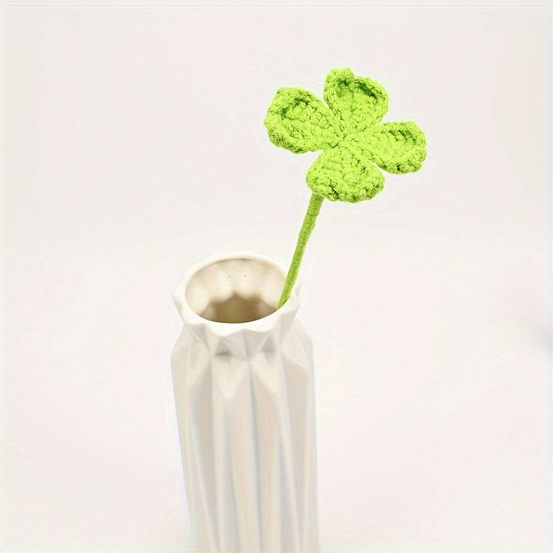 Bright green crocheted four-leaf clover in a minimalist white ceramic vase