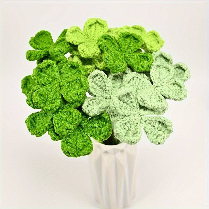 Crocheted green clover leaves in varying shades, arranged in a white vase