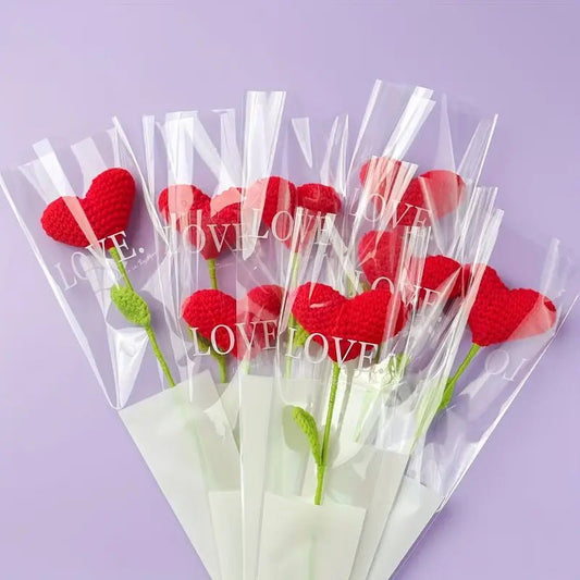 Red crocheted heart roses in clear plastic sleeves with "LOVE" text, on lavender background
