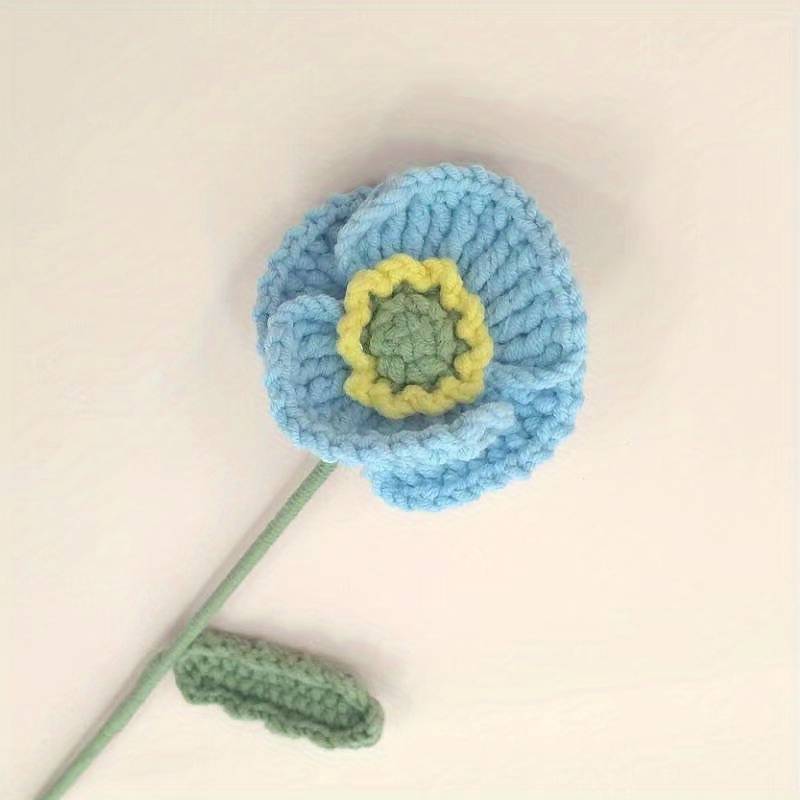 Crocheted blue flower with yellow and green center on soft background