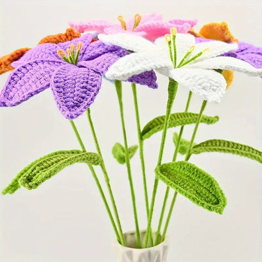 Crocheted flowers in purple, white, and pink with green stems in a small vase