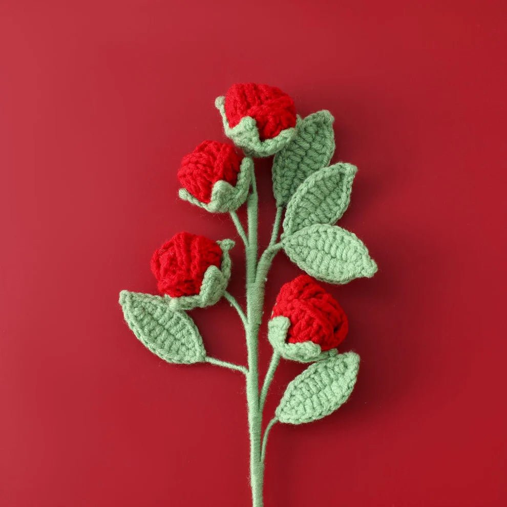 Crocheted red roses with green leaves on a vibrant red background