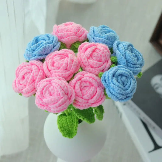 Crocheted rose bouquet in pink and blue, nestled in a white vase with green leaves
