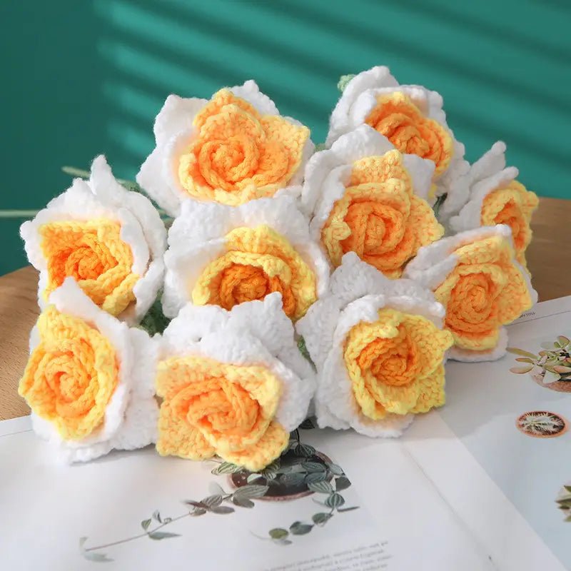 Crocheted yellow and white roses on a teal background and botanical paper