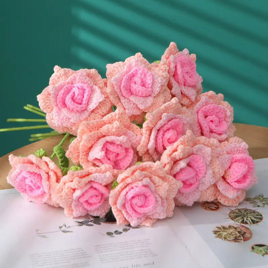 Crocheted pink roses in soft shades, bundled together on a textured surface
