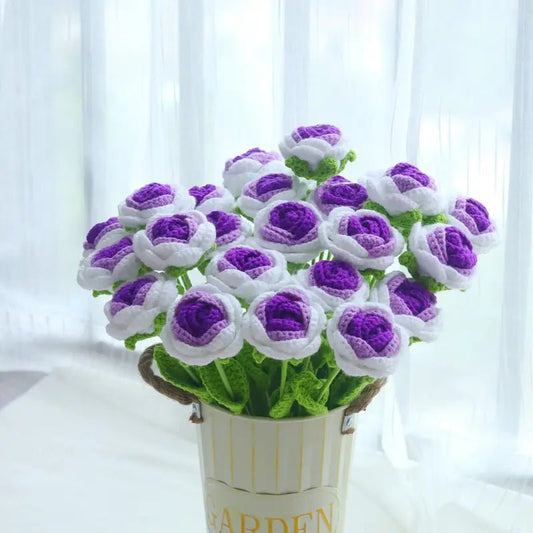 Crocheted purple and white flowers in a white "Garden" pot near soft curtains