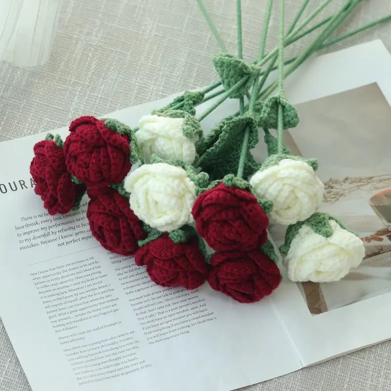 Crocheted red and white roses with green stems on an open book page