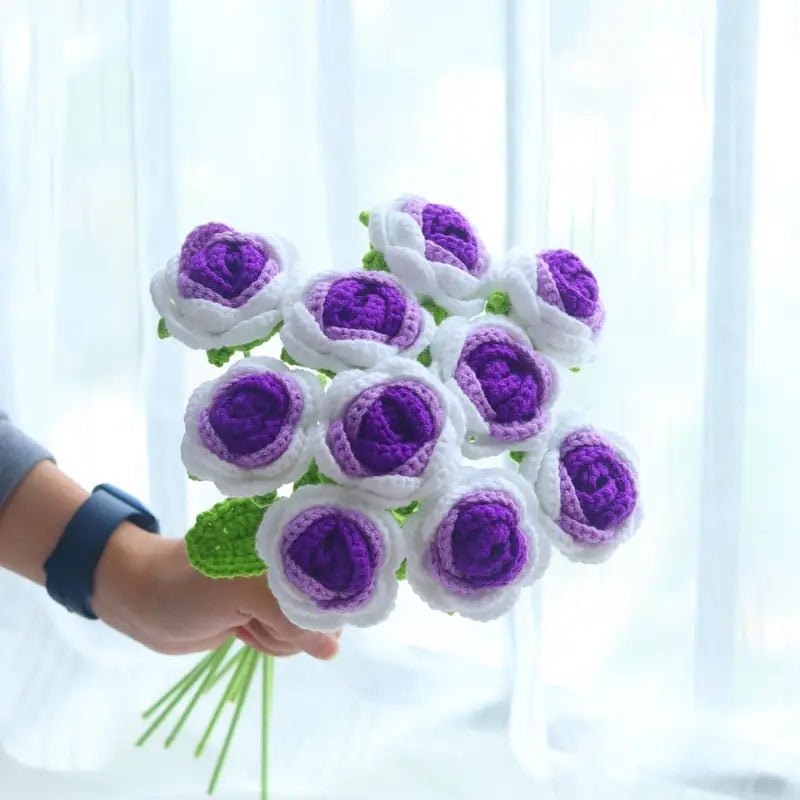 Crocheted bouquet of white and purple flowers held by a hand