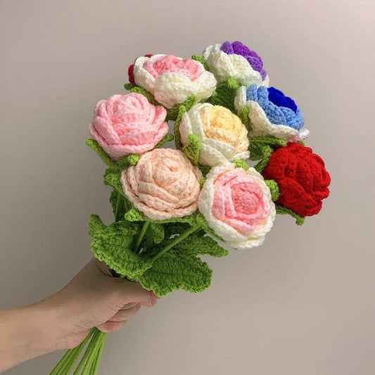 Crocheted bouquet of colorful roses with green stems held by a hand