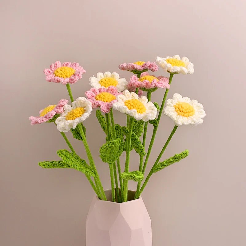 Crocheted daisies in white and pink, with green stems, arranged in a pale pink vase.
