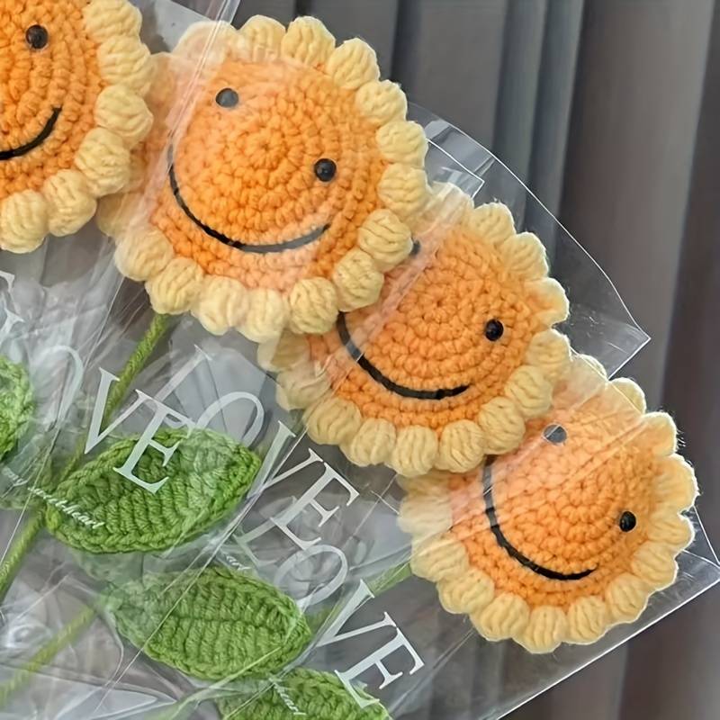 Crocheted smiling sunflowers with yellow petals and orange centers in clear packaging