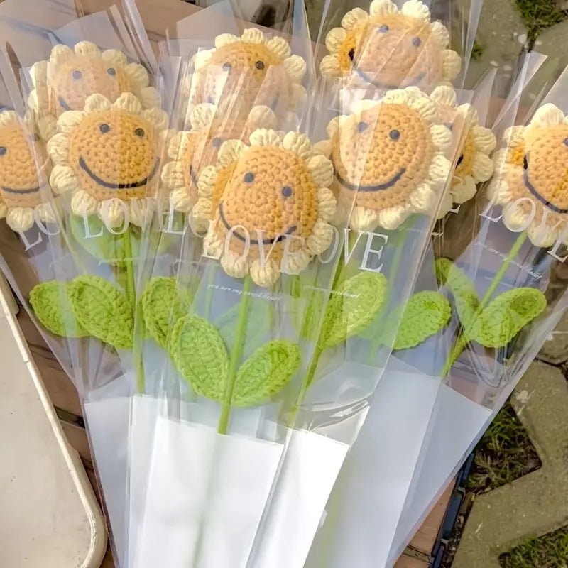 Crocheted sunflowers with smiley faces in clear packaging, green stems and leaves