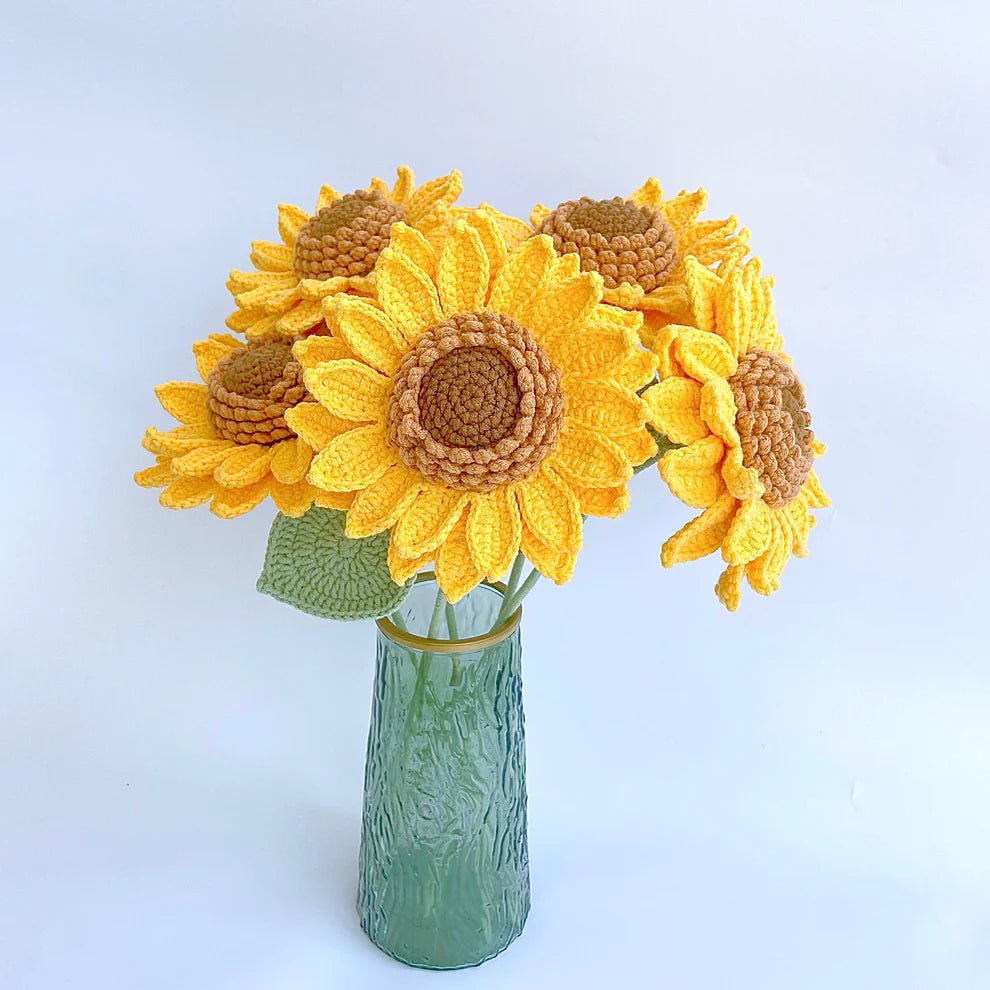 Crocheted yellow sunflowers with brown centers in a green textured glass vase