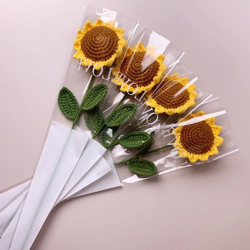 Crocheted sunflowers in clear wrapping, bundled with green leaves on white background