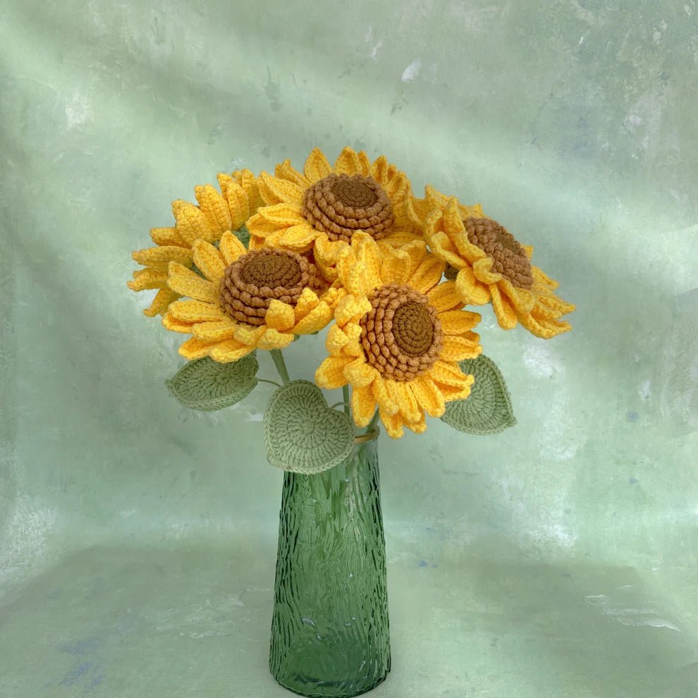 Crocheted sunflowers in textured green glass vase against soft seafoam background