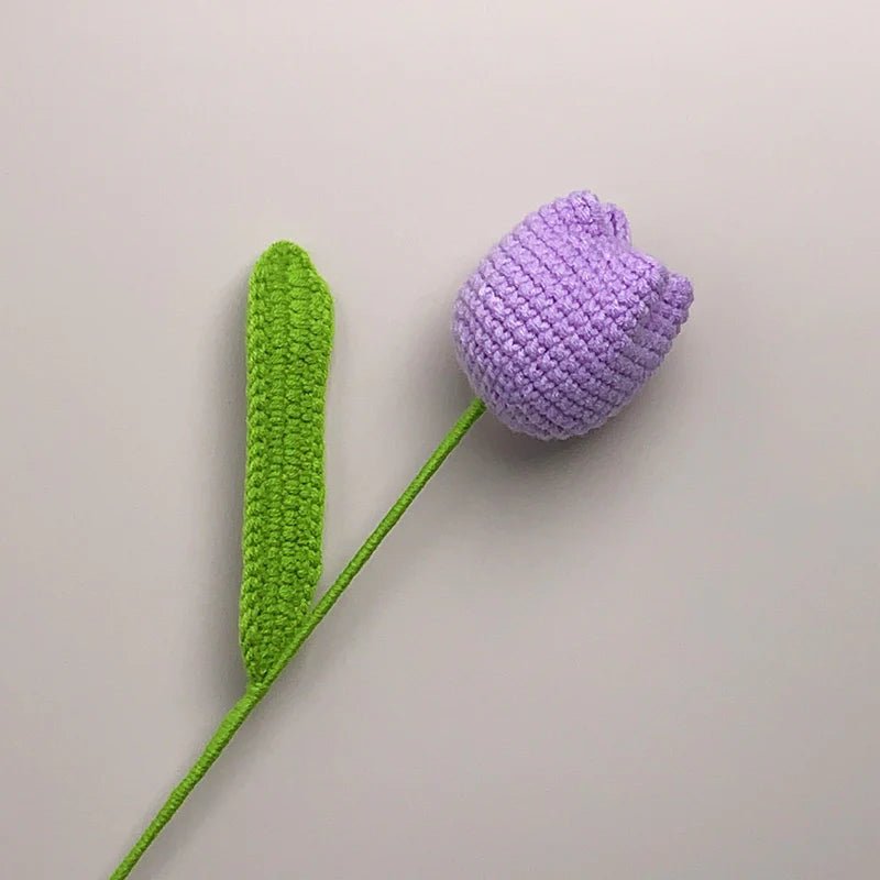 Crocheted purple tulip with green stem against a neutral background