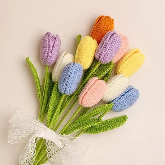 Crocheted tulips in pastel colors tied with lace ribbon on light background