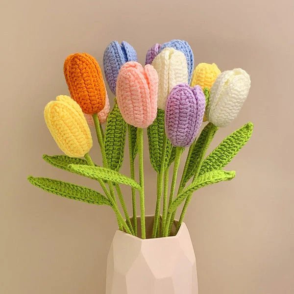 Crocheted tulips in pastel colors with green stems, arranged in a white geometric vase.