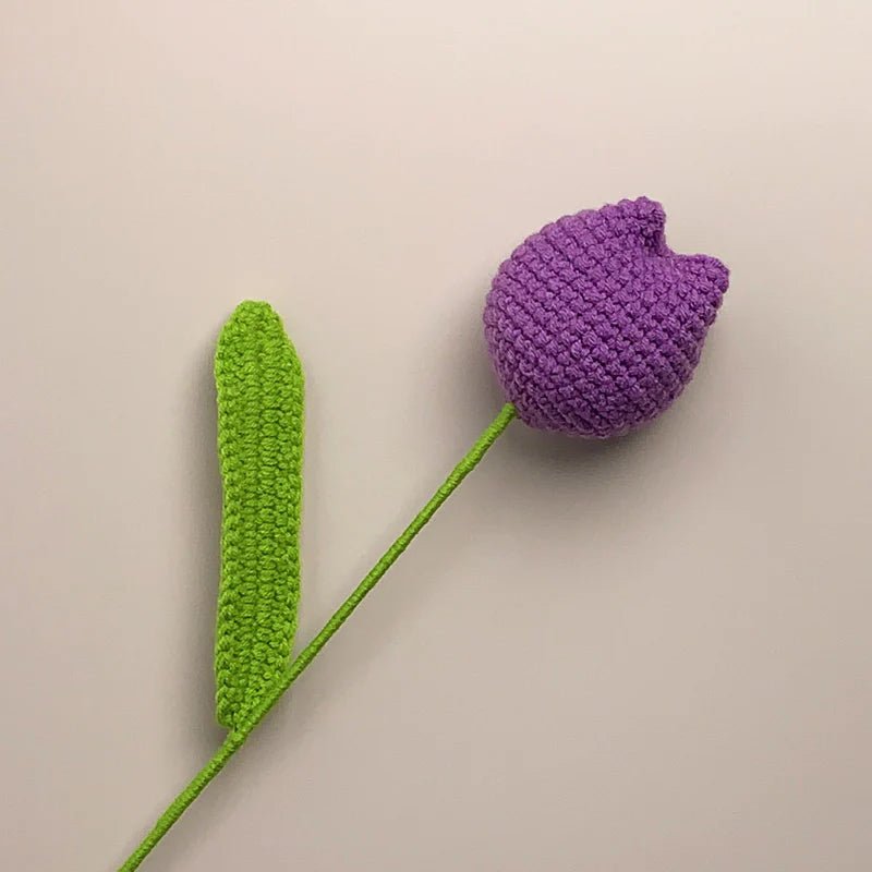 Crocheted purple tulip with green stem on neutral background