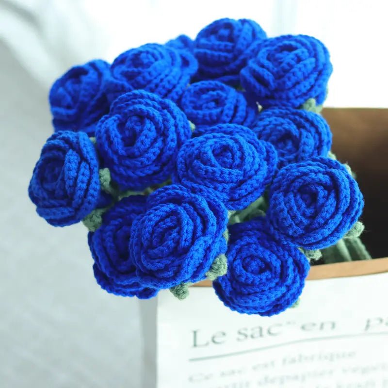 Crocheted blue roses clustered together on a book with French text