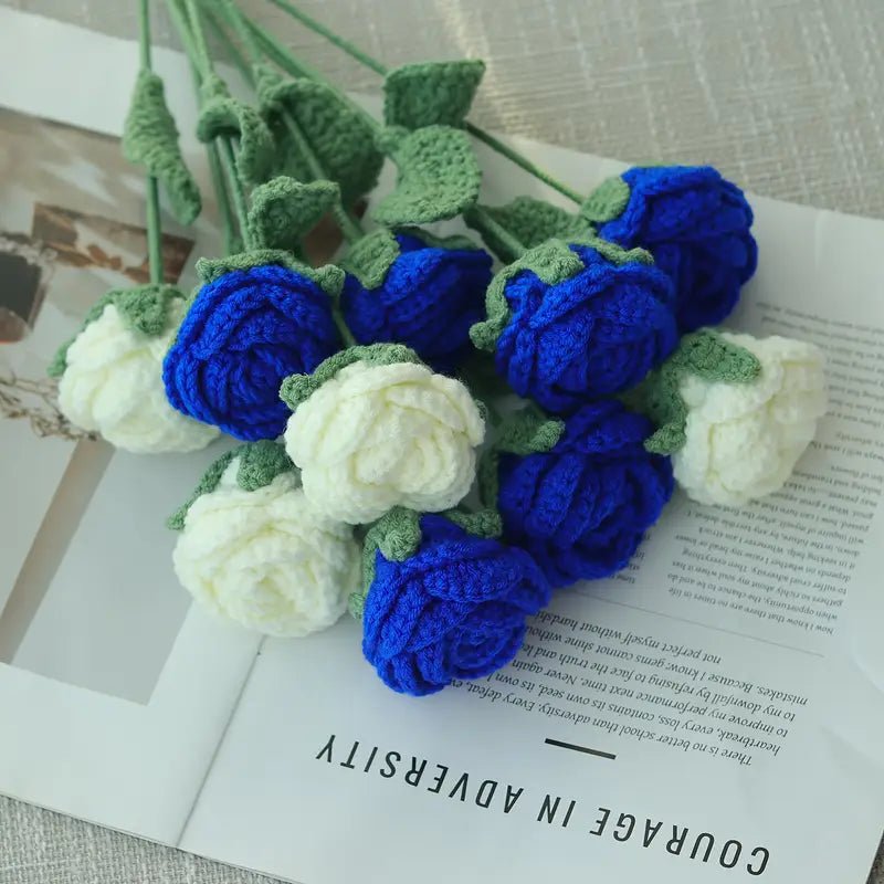 Crocheted blue and white roses with green leaves on an open book page