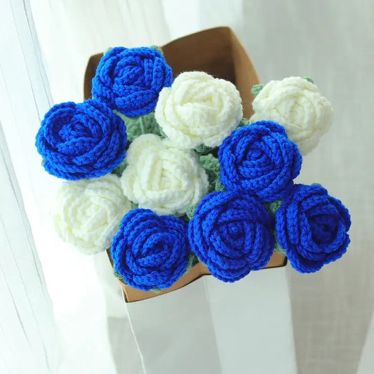 Crocheted blue and white roses in a white vase against a light background