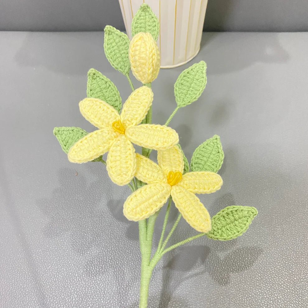 Crocheted yellow flower with green leaves, handmade yarn craft against textured background