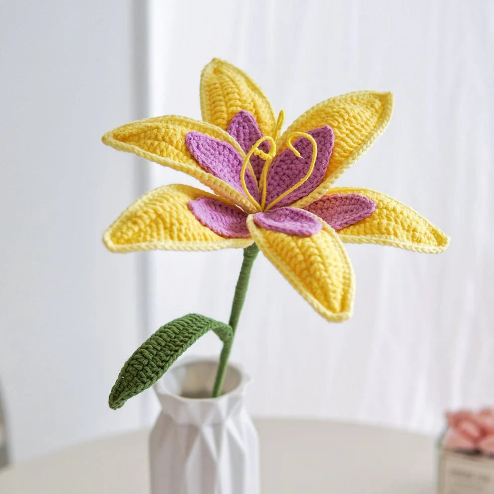 Crocheted yellow and purple lily with green stem in white ceramic vase