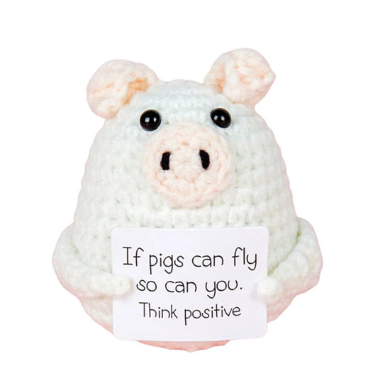 Crocheted white pig holding a motivational "Think positive" sign with playful message
