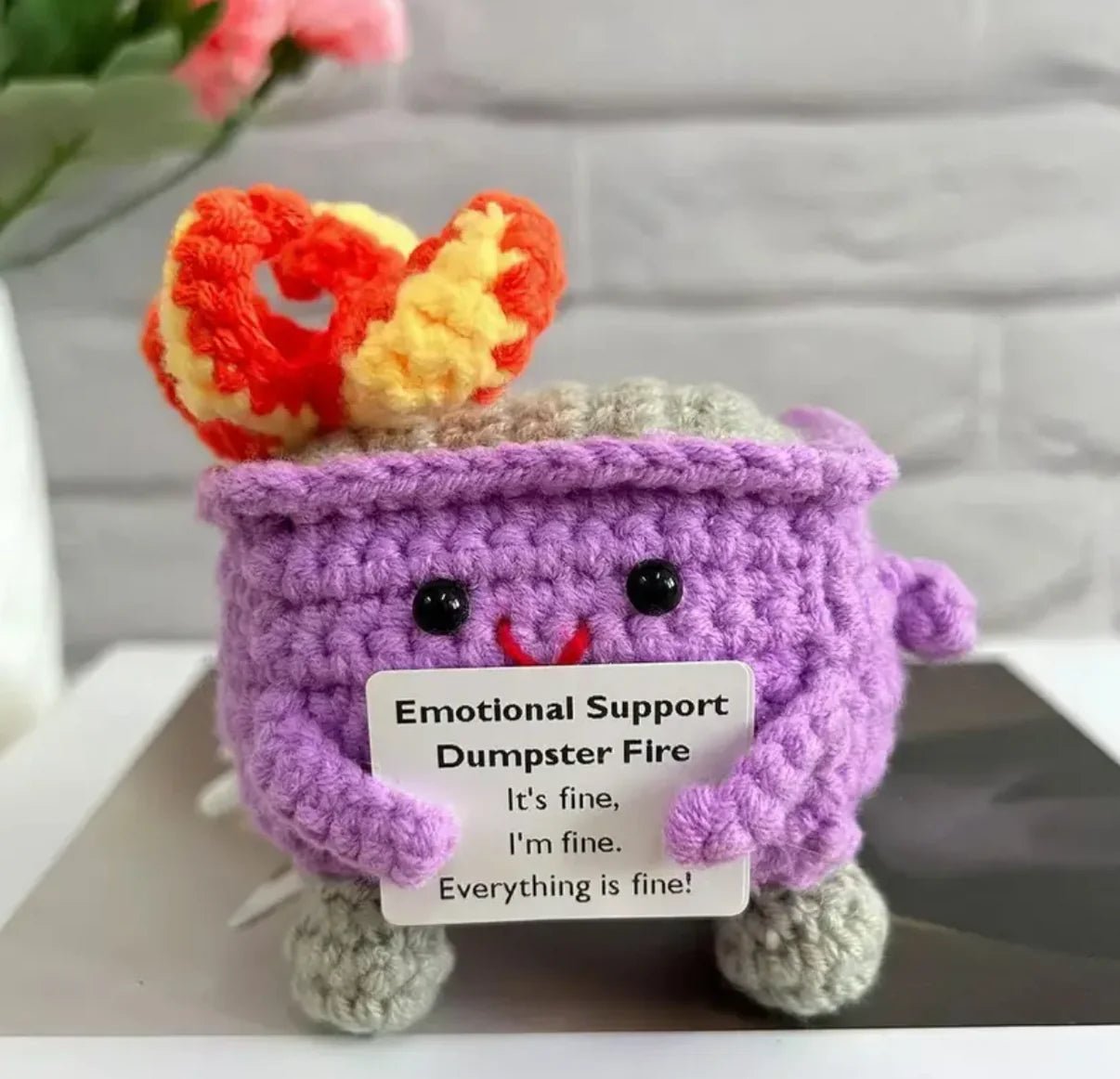 Crocheted purple dumpster fire with humorous "Emotional Support" label and cute face
