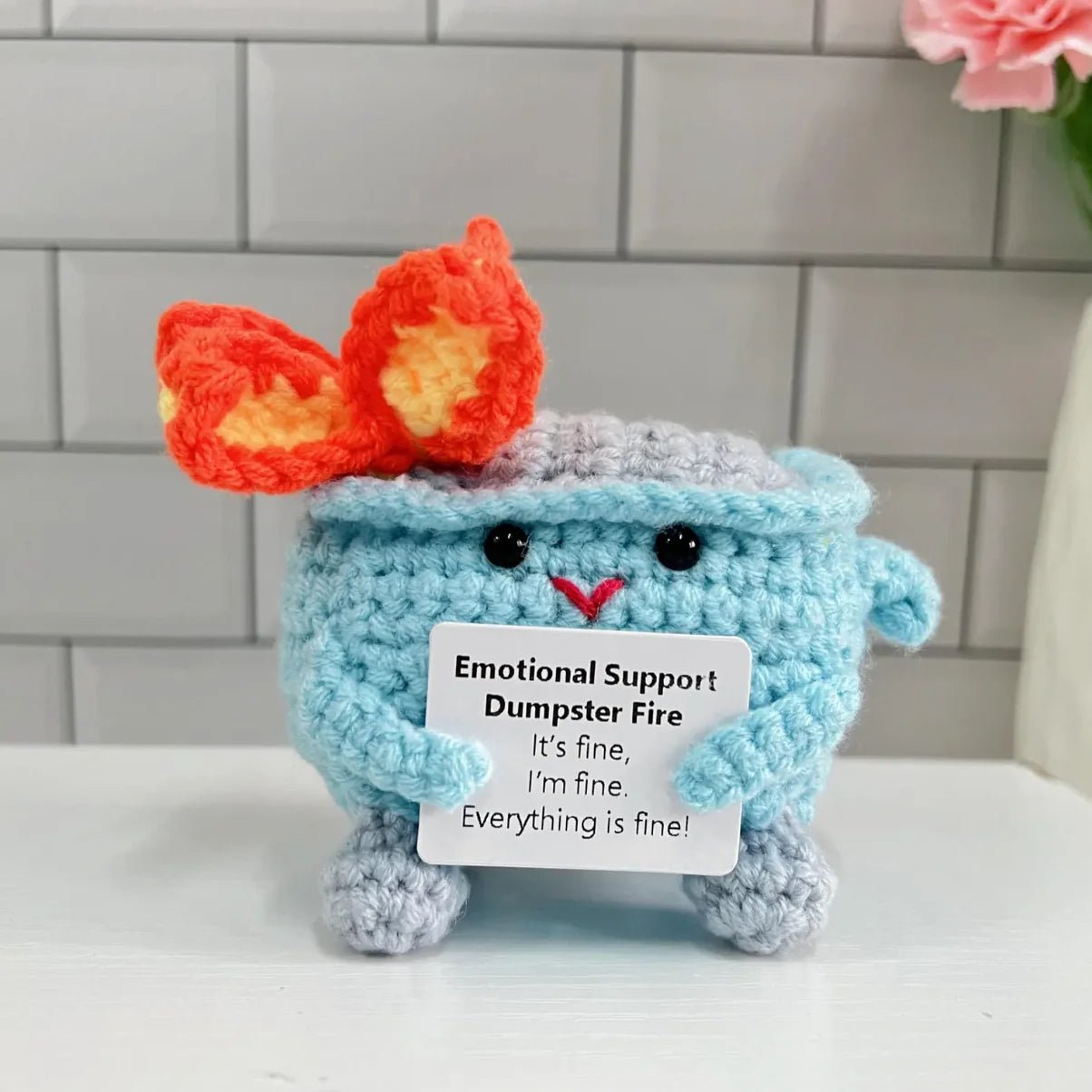 Crocheted blue dumpster with flames, holding "Emotional Support Dumpster Fire" sign