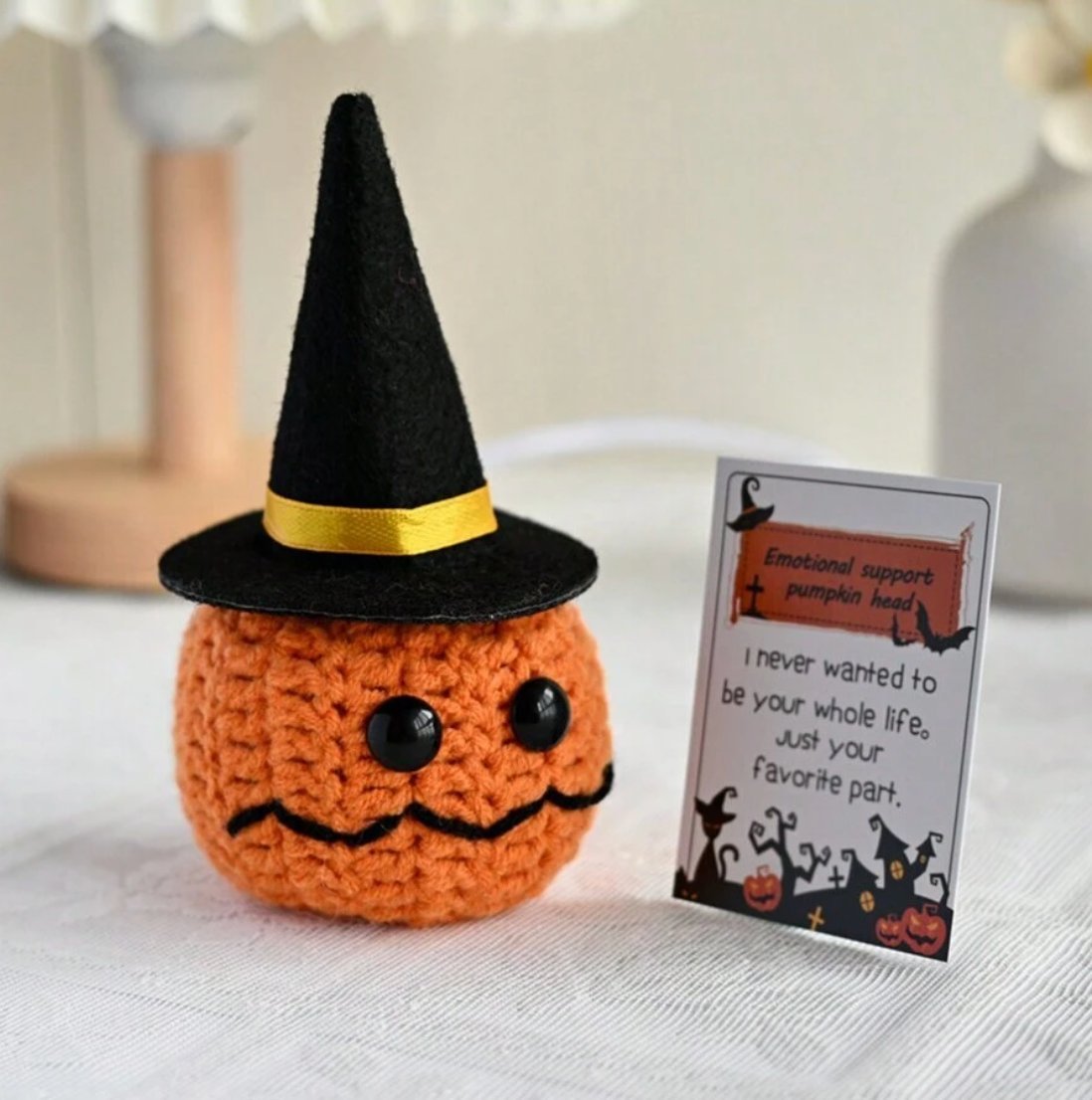 Crocheted orange pumpkin with witch hat and funny emotional support card next to it