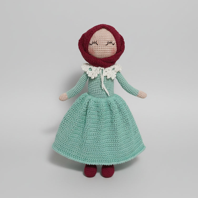 Crocheted doll in mint green dress with red bonnet and white ruffled collar