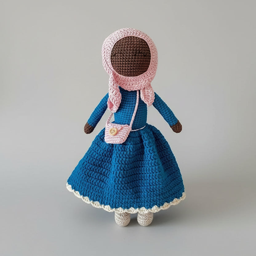 Handmade crocheted doll in blue dress with pink bonnet and small shoulder bag