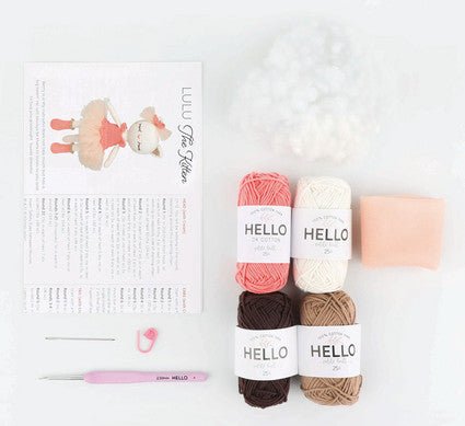 Knitting supplies with pink, white, brown yarns, pattern, and crochet hook on white background