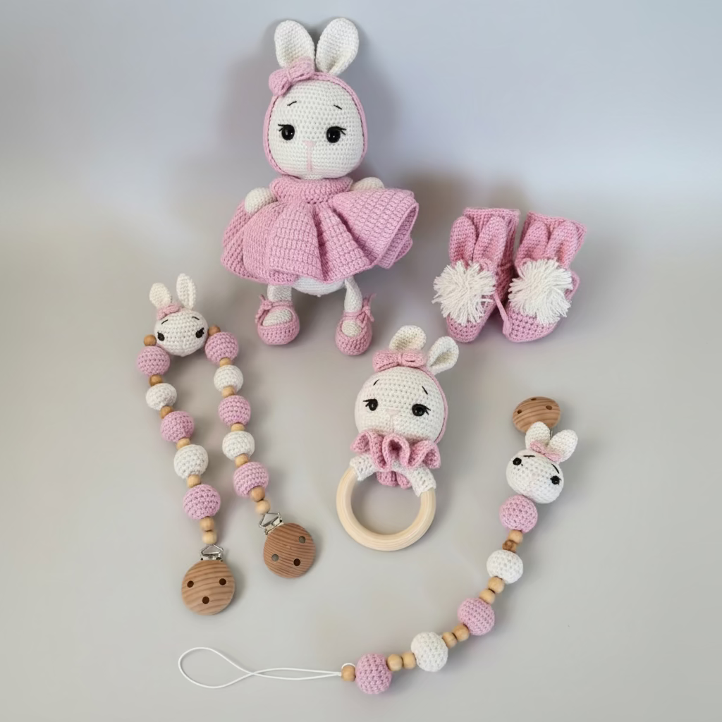 Set of baby toys including a crocheted rabbit, teether, and rattle on a light gray background