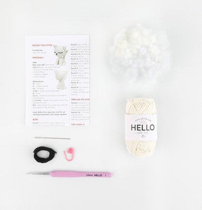 Knitting pattern, white yarn, pink crochet hook, and black elastic on white background