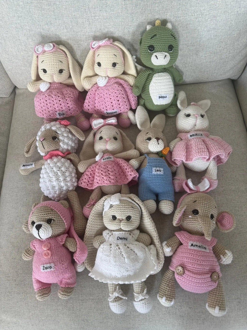 Handmade crocheted stuffed animals in pink, white, and green, with personalized name tags