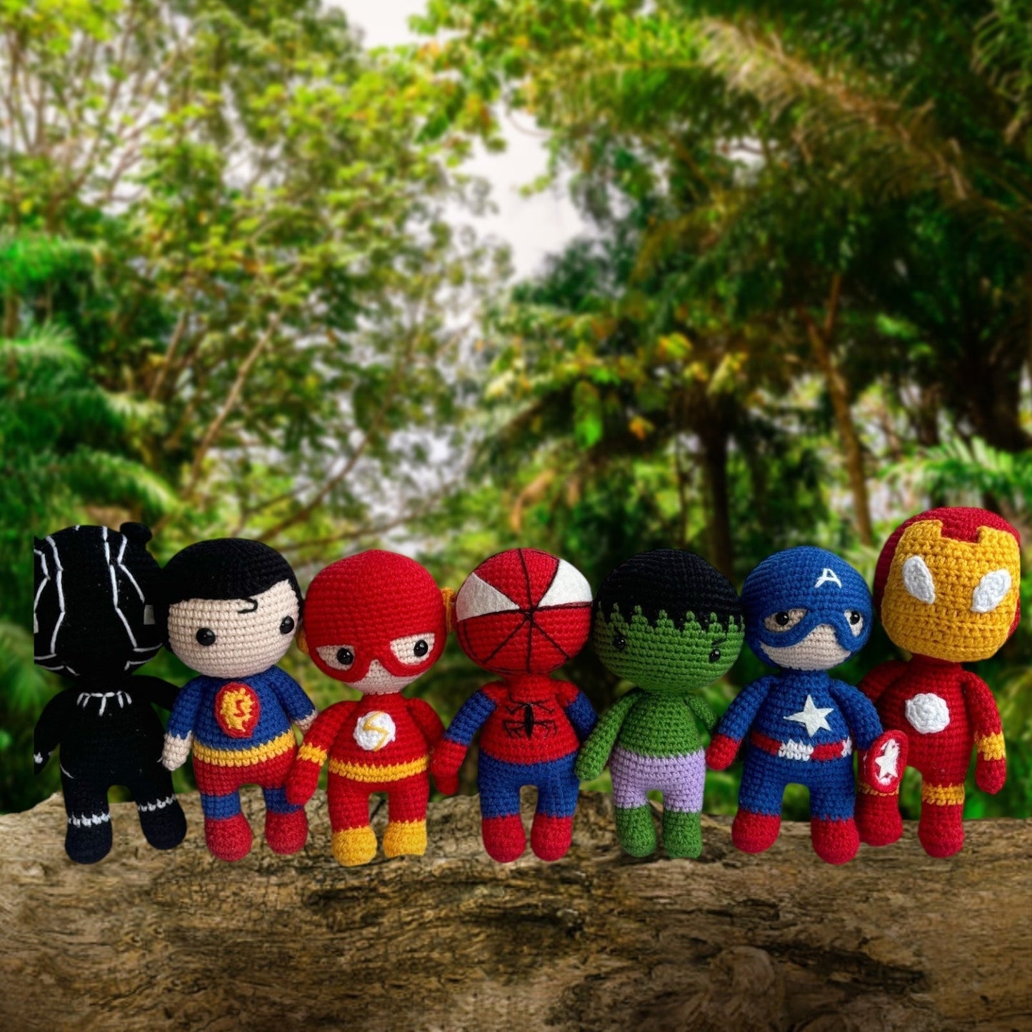 Crocheted Marvel superheroes sitting together on a log in a lush green forest