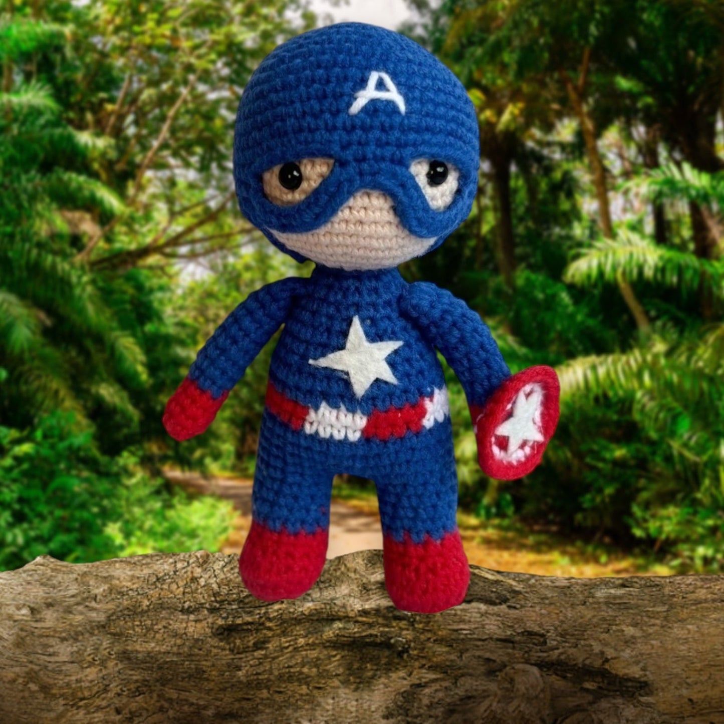 Crocheted superhero doll in blue and red, standing on a tree branch in a forest.