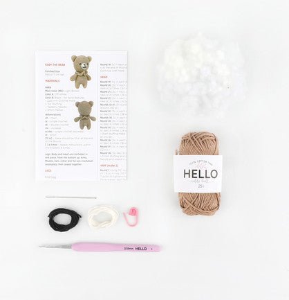 Knitting supplies for making a teddy bear, including yarn, pattern, and crochet hook