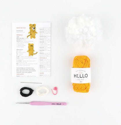 Crochet kit with yellow yarn, pattern, hook, and notions on white background