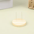 Two thin metal pins standing upright in a round wooden base on a light surface.