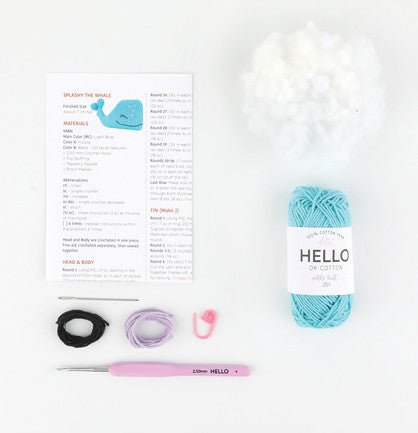 Crochet supplies: yarn, pattern, crochet hook, and elastic bands laid out on white background