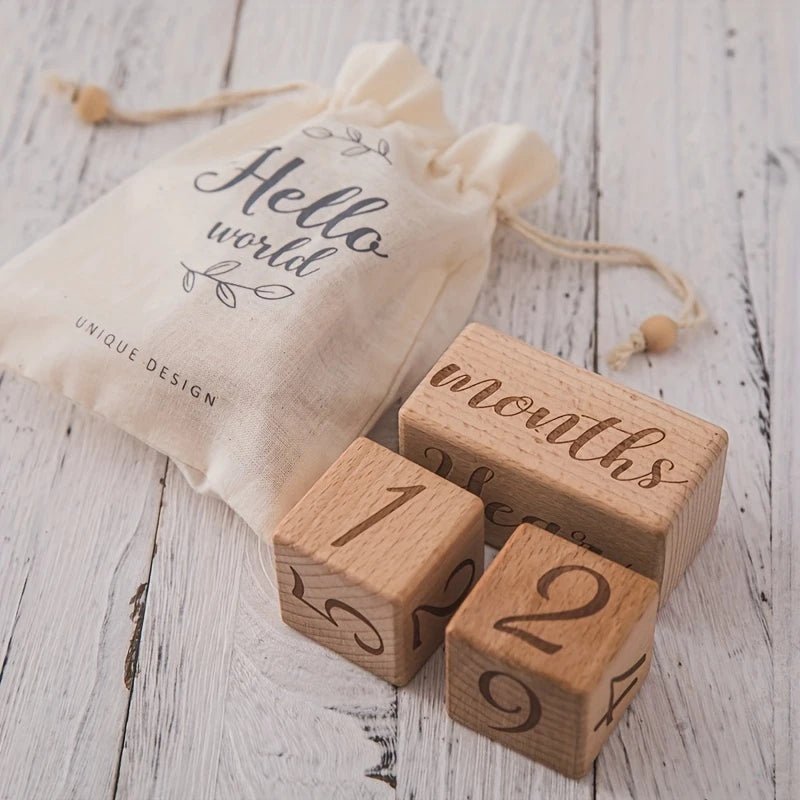 Wooden milestone blocks with "months" block and "Hello world" bag on wooden surface